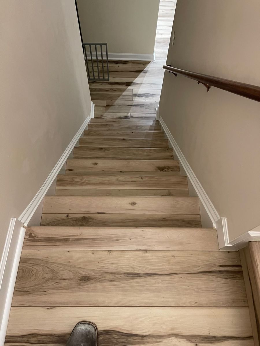 Staircase finished in light hickory luxury vinyl plank with white trim